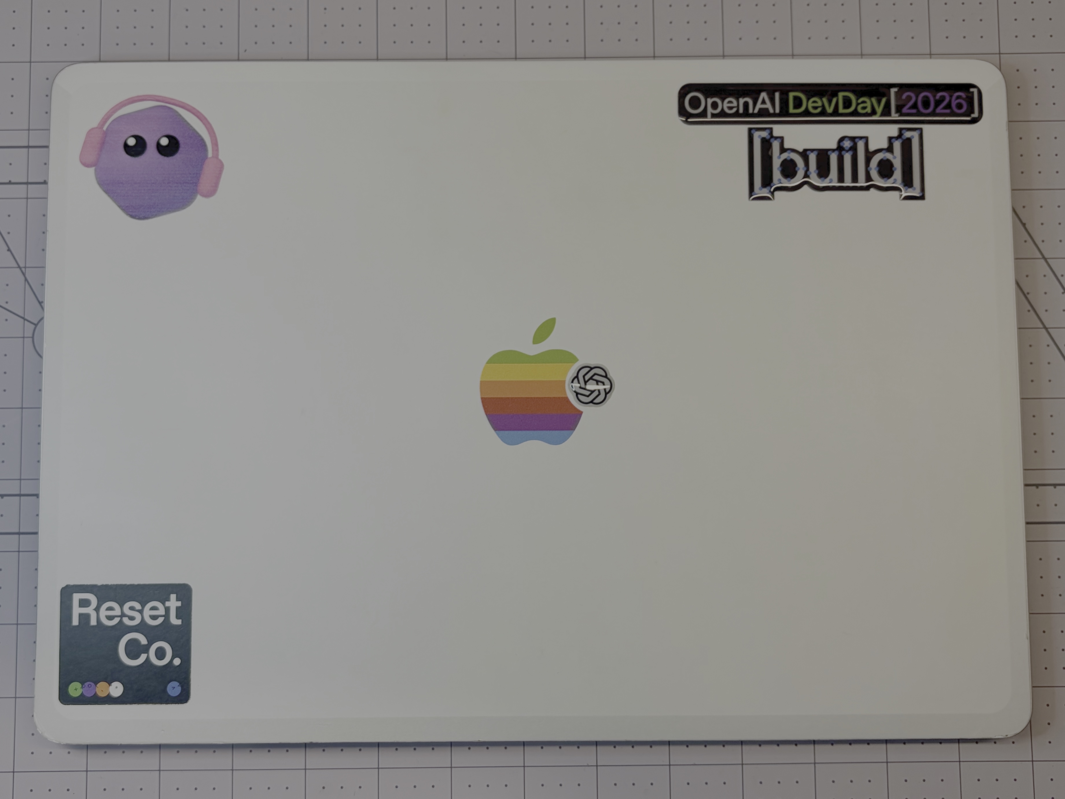Brad’s MacBook Air with AVA wearing headphones in the top left and OpenAI DevDay 2026 stickers.