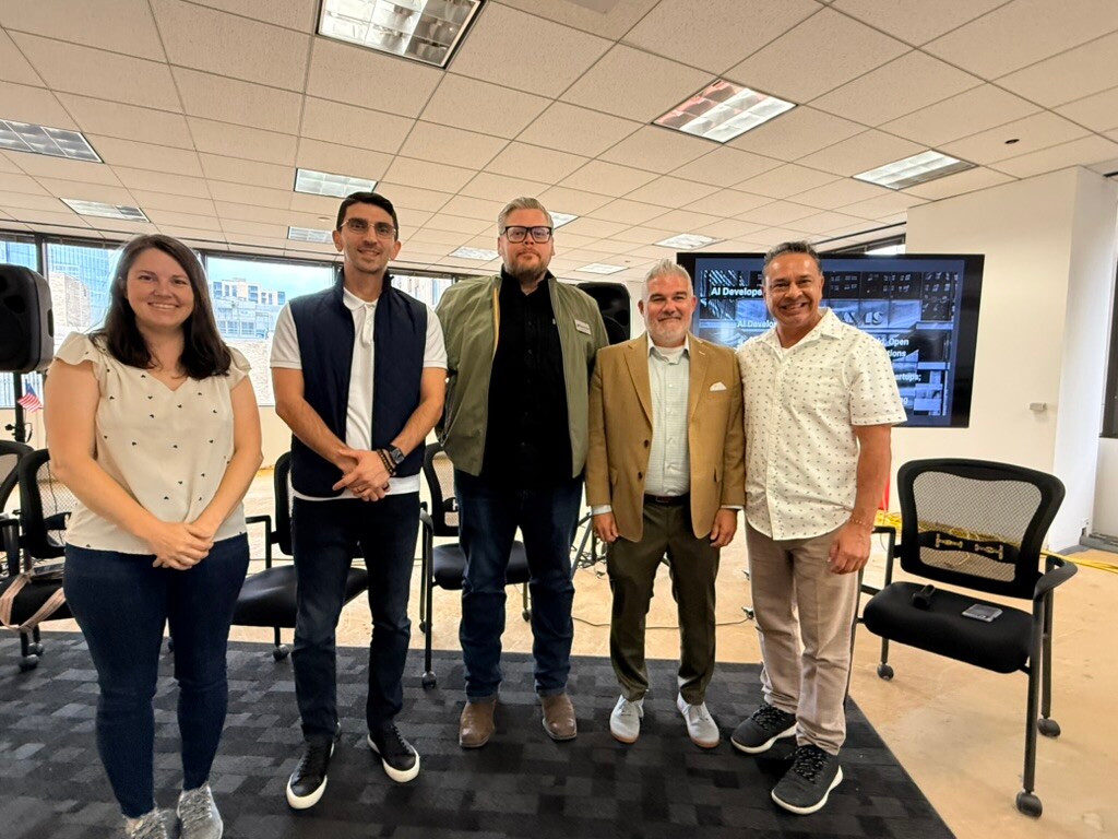 Five attendees stand together beside an AI Developer Ecosystems display at The Innovation Hub in Houston.